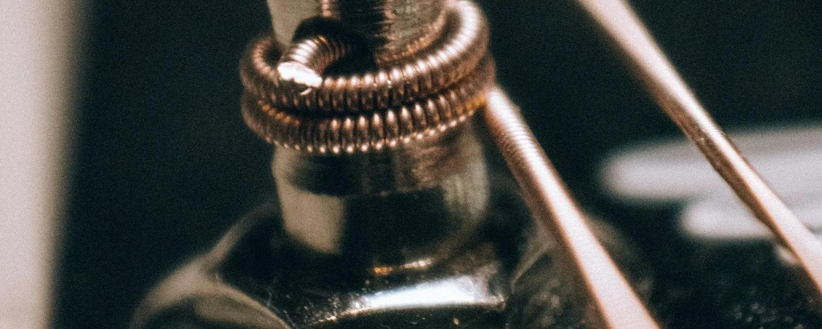 A guitar string wound around a machine head post, in shallow focus